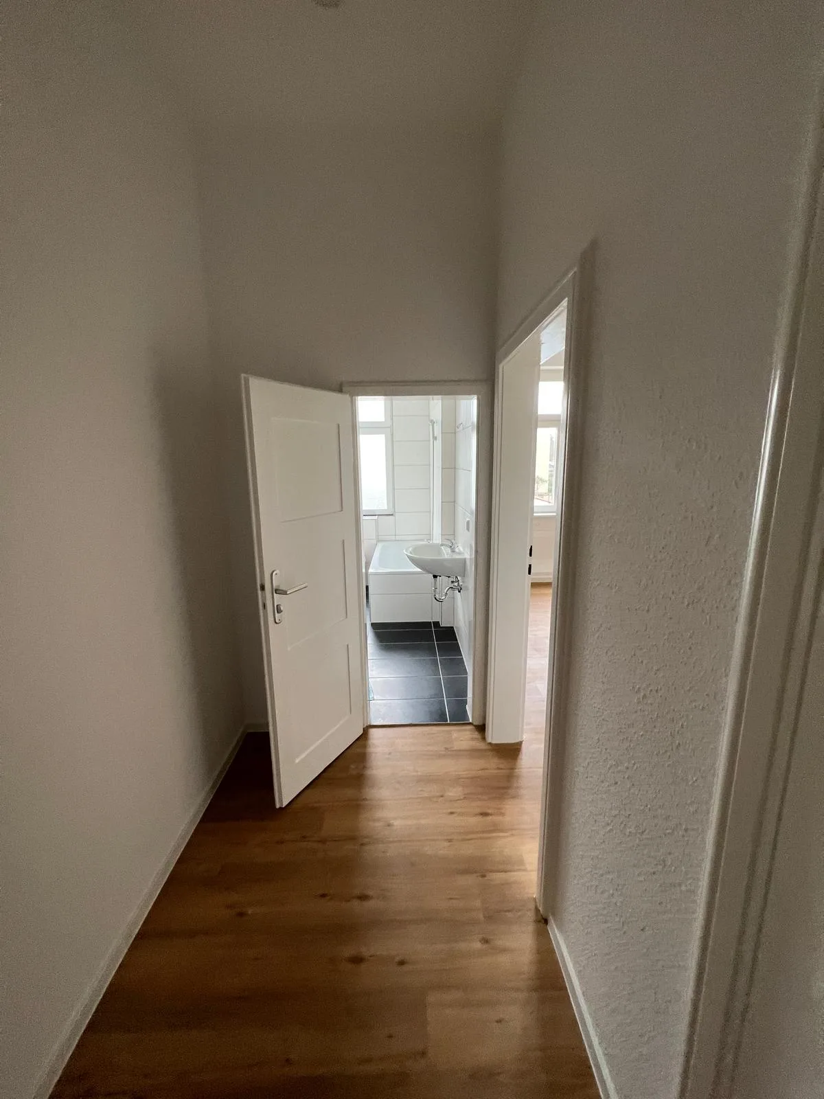 Fertig saniertes Badezimmer mit dunklen Bodenfliesen und weißer Wandverfliesung